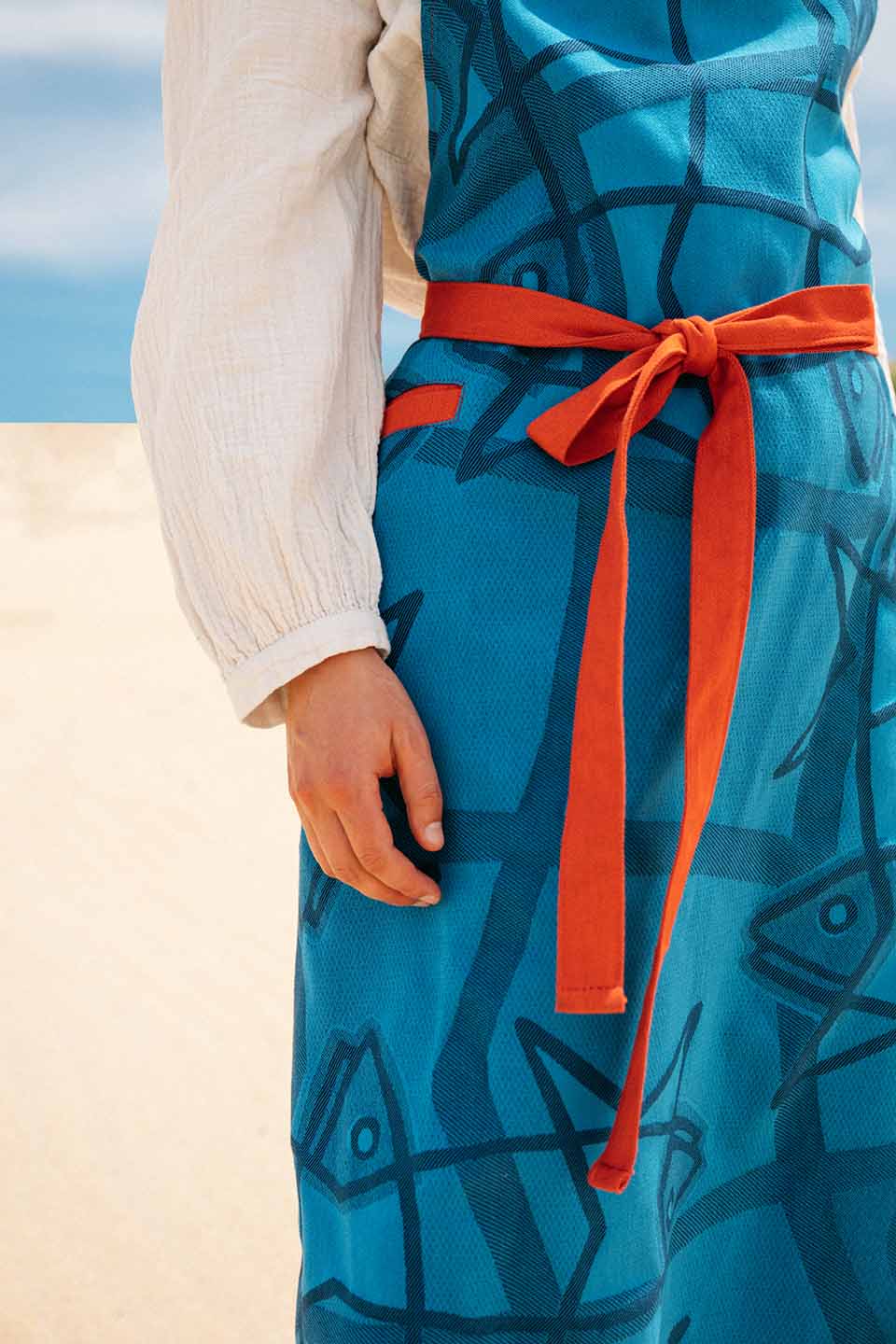 Grand tablier mer. De couleur bleu avec des sardines dessinées dessus.